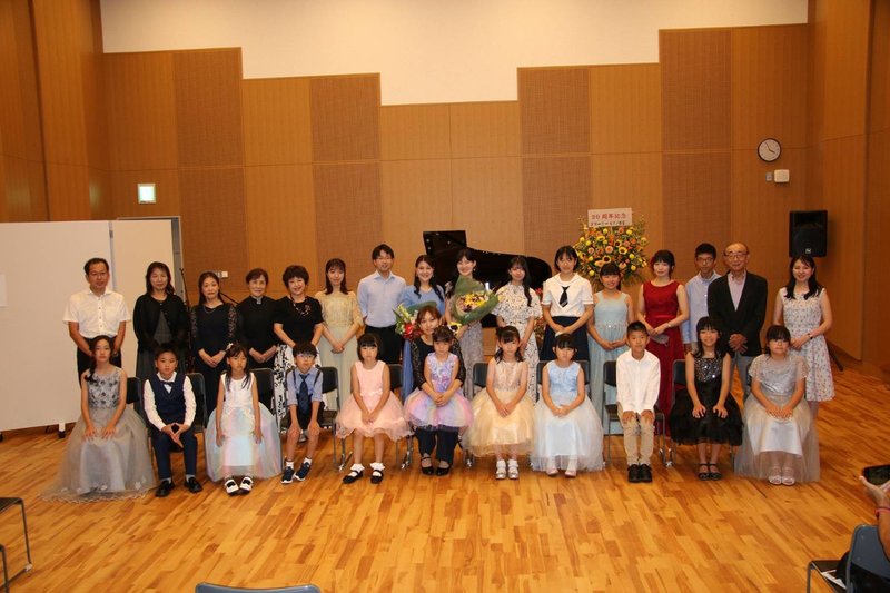 夏の発表会、生徒さん全員での集合写真。ドレスアップした子どもたちが舞台に並ぶ